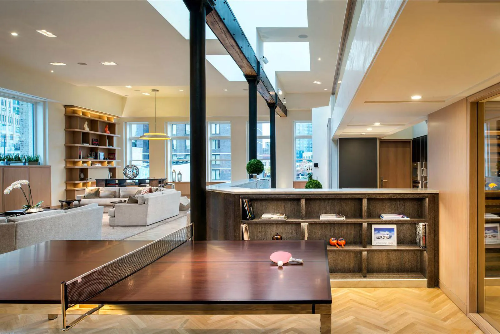 Loft living area with a ping-pong table, exposed beams, skylights, and large windows.