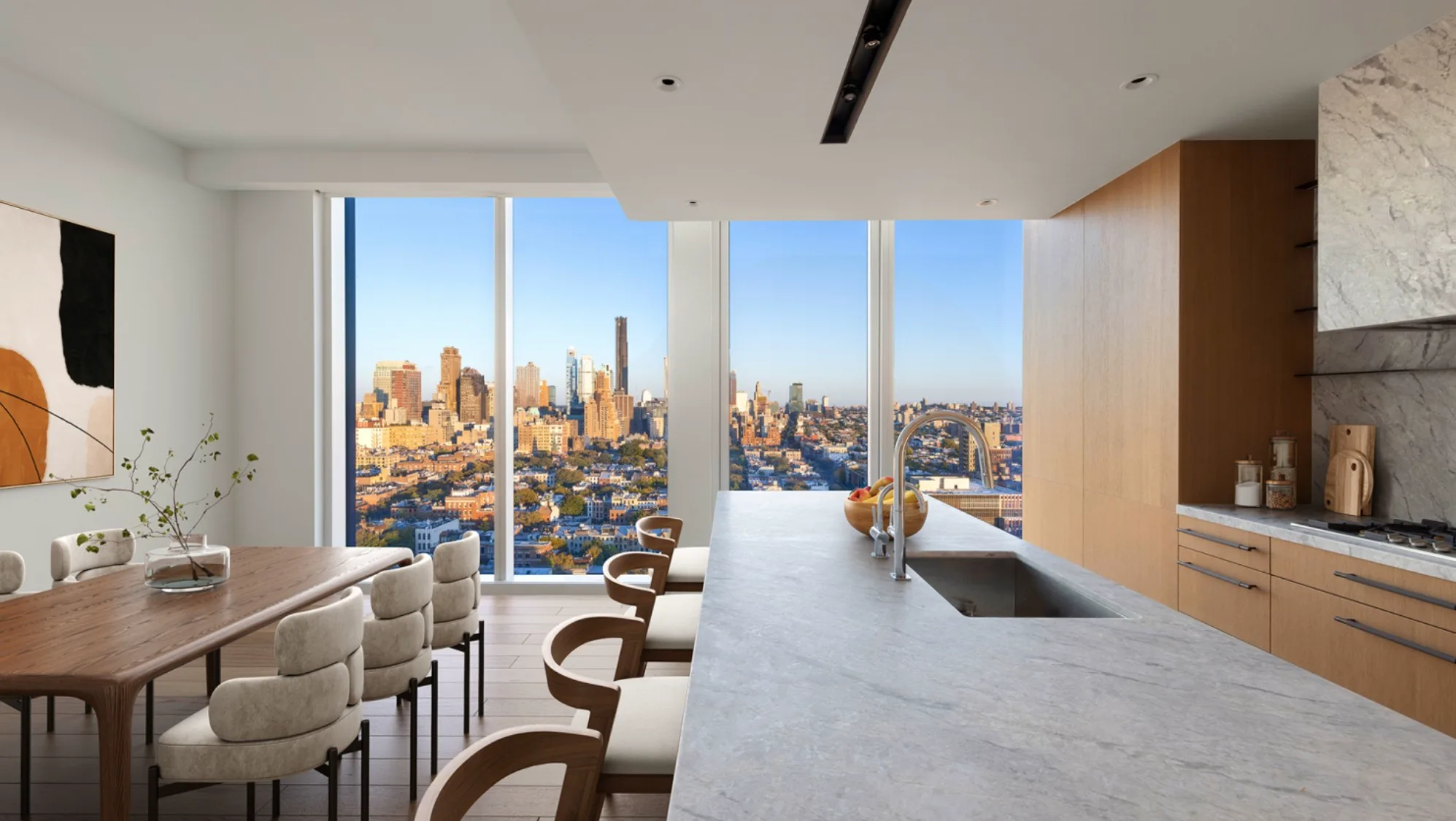 Modern kitchen and dining area with a stone island and expansive city skyline views.