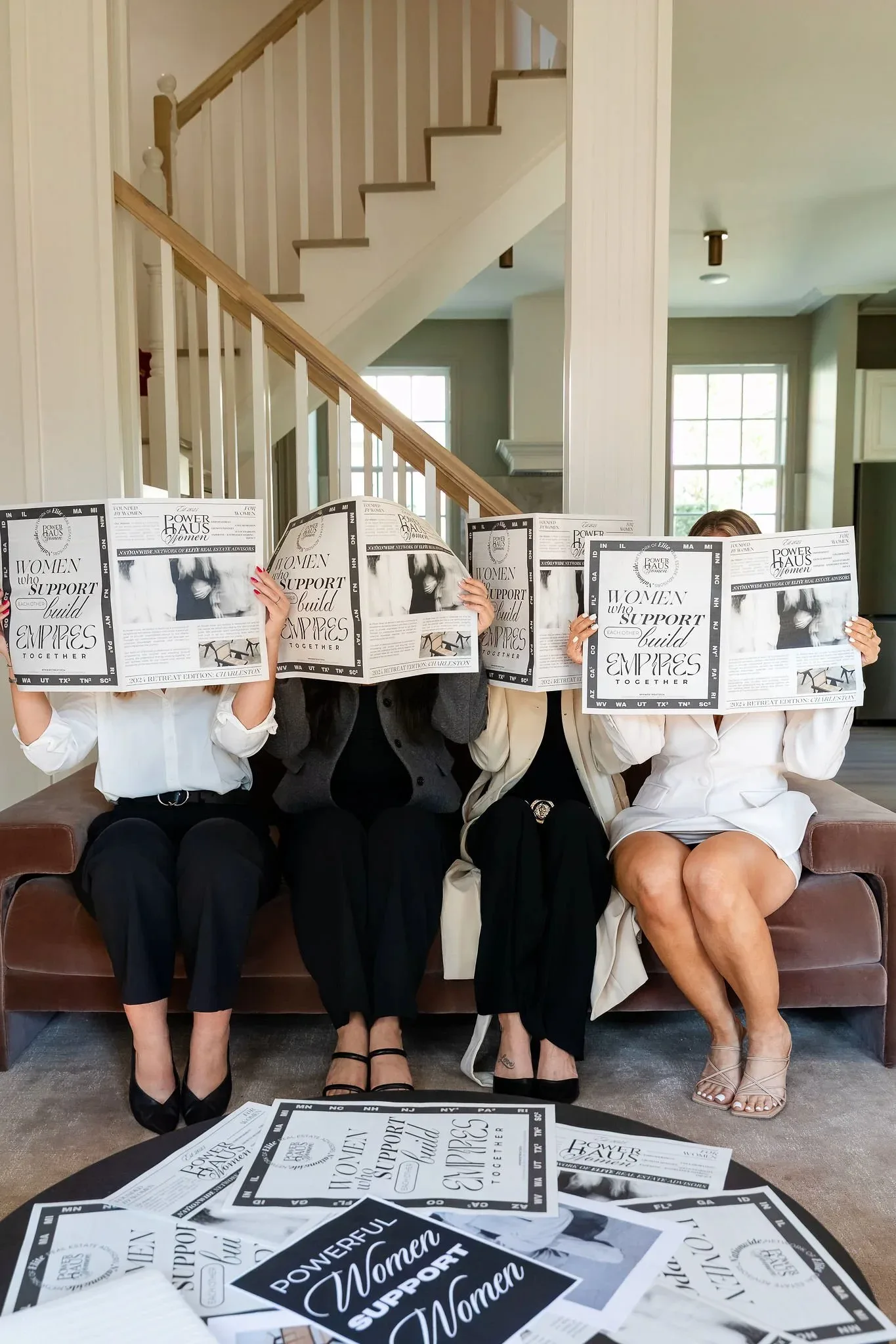 Four women hold Power Haus Women publications while seated together on a couch.